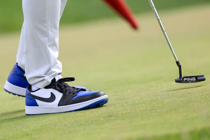 Side view of white, black, and blue Air Jordan golf shoes.